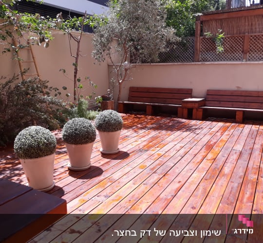 רצפת עץ עם ספסלים ועציצים בגינה